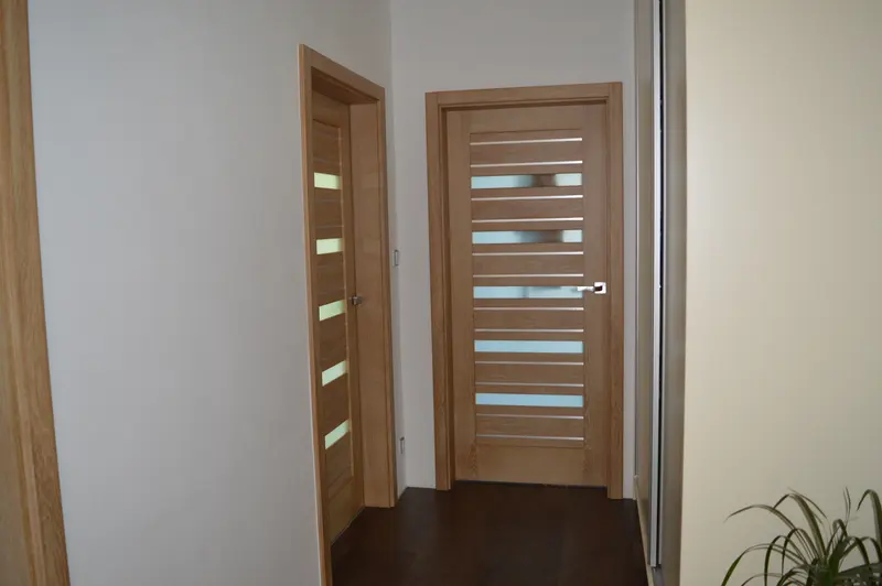 Dvoje dubové interiérové dveře s prosklenými pruhy na chodbě