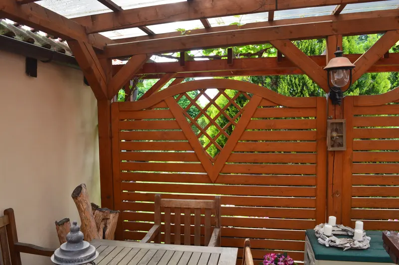 Pergola s dřevěnou mřížovou zástěnou, lucernou a zahradním posezením