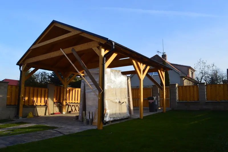 Velká dřevěná pergola se sedlovou střechou jako zastřešené stání na zahradě