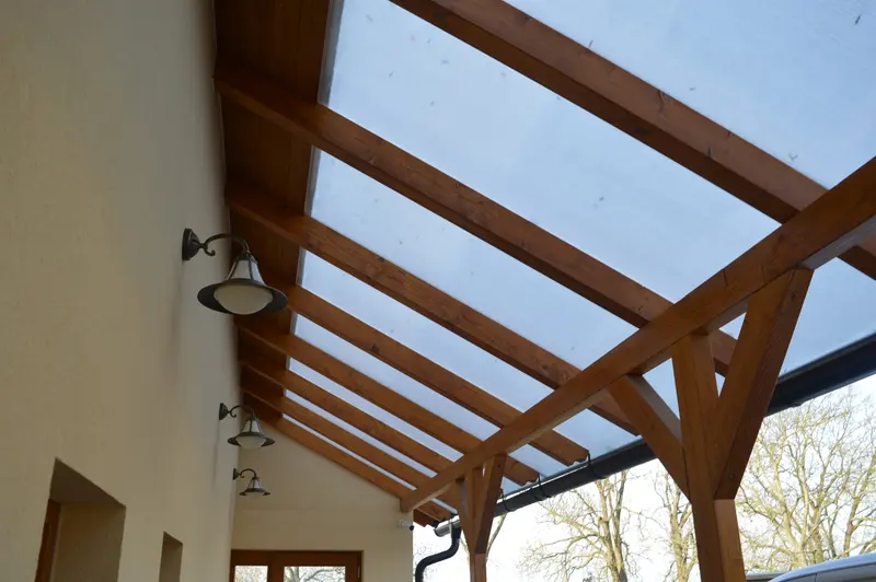 Dřevěná pergola s průsvitnou polykarbonátovou střechou přistavěná k domu