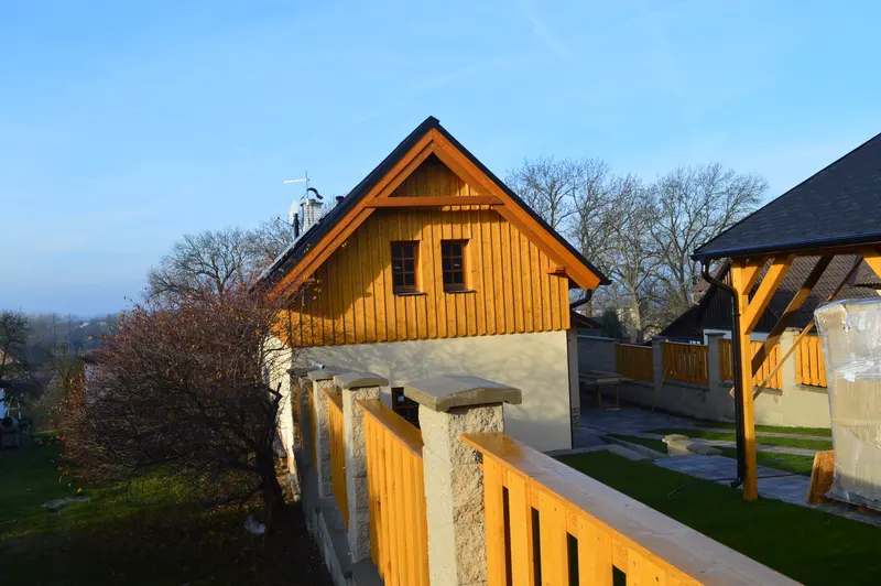 Dřevěný plot s kamennými sloupky a pergola na zahradě u roubeného domu